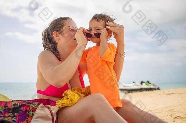 年轻的高加索女孩戴着粉色眼镜，穿着粉色比基尼泳衣，在海浪的背景下戴上<strong>儿童眼镜</strong>