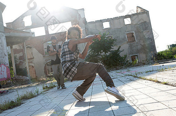 年轻的非裔美国人在城市<strong>广场</strong>上与一位朋友跳嘻哈<strong>舞</strong>，背景是高楼上明亮的阳光