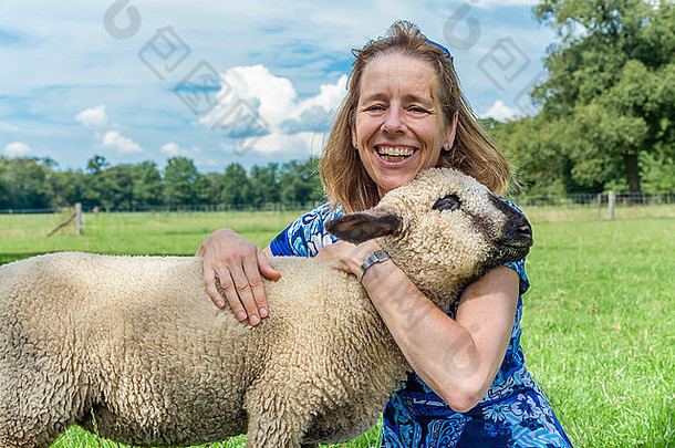 欧洲妇女在草地上拥抱绵羊
