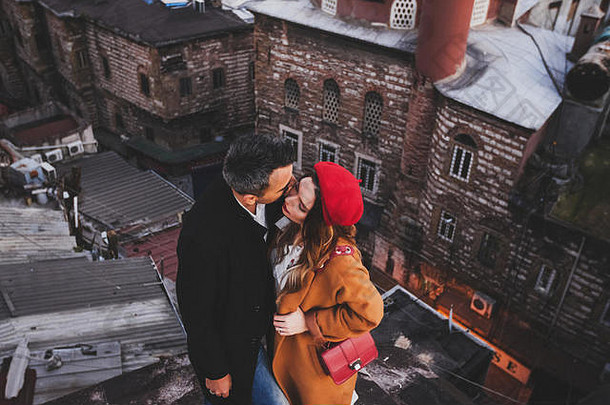 夫妇爱拥抱屋顶视图晚上城市背景休闲风格秋天红色的贝雷帽米色外套