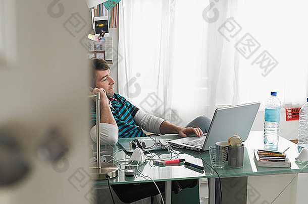 办公人员使用手机和笔记本电脑坐在办公桌旁，视野开阔