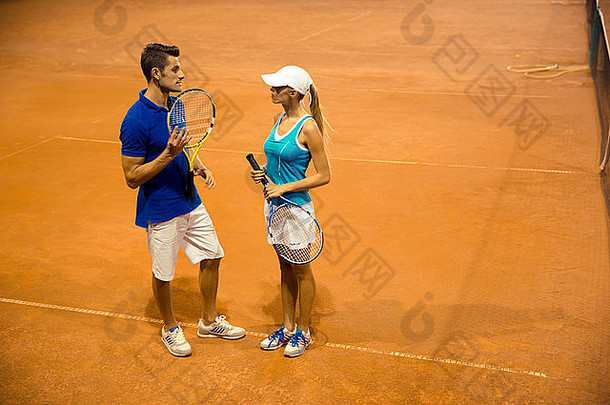 两名网球运动员在球场上用球拍交谈的肖像