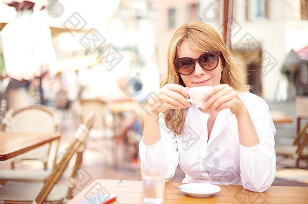 迷人的中年妇女在咖啡馆喝<strong>速递</strong>咖啡的画像。