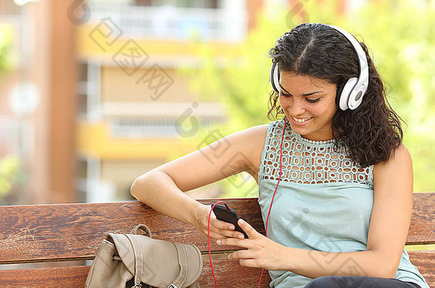 女人听音乐聪明的电话耳机公园