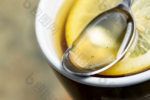 金色蜂蜜的水平特写照片，在汤匙里，在热<strong>茶</strong>里放着新鲜的柠檬片