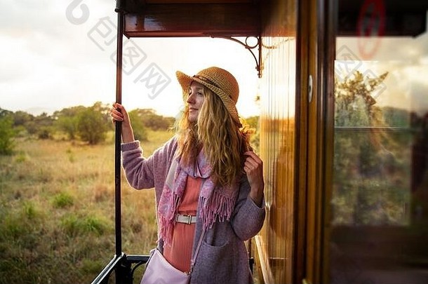 戴草帽的年轻女子乘坐复古木制火车旅行。夕阳的风景，金色头发的风。女孩高兴地笑着。西班牙马略卡岛。