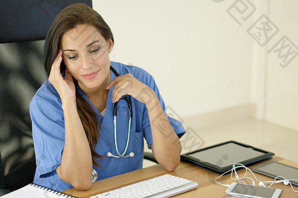 一名穿着scrubs的<strong>医护人员坐</strong>在电脑前