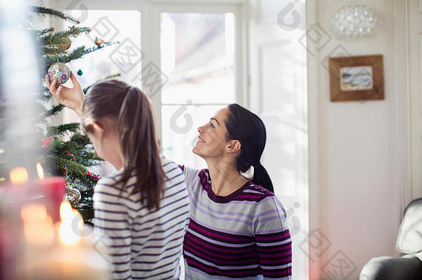 母亲和女儿在装饰圣诞树