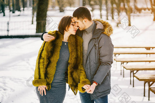 一对幸福的夫妇在一个阳光明媚的冬日穿过公园