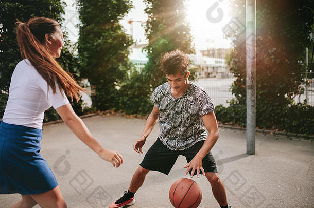 两名年轻男女在<strong>篮球</strong>场上带球运球。朋友们在球场上打<strong>篮球</strong>，玩得很开心。