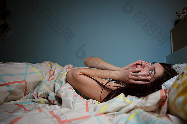 年轻的女人说谎床上痛苦失眠嘈杂的邻居压力报警声音防止睡眠概念