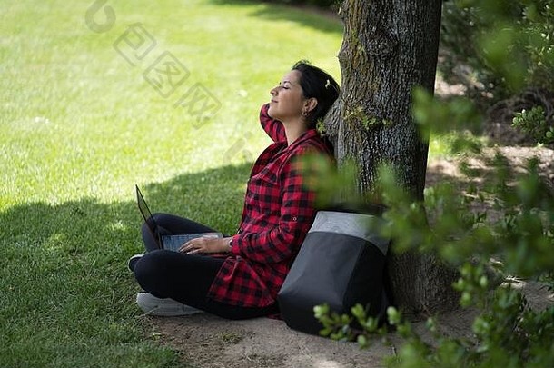 <strong>年轻的</strong>女人坐着树电脑腿<strong>伸</strong>展运动放松公园自然环境技术概念
