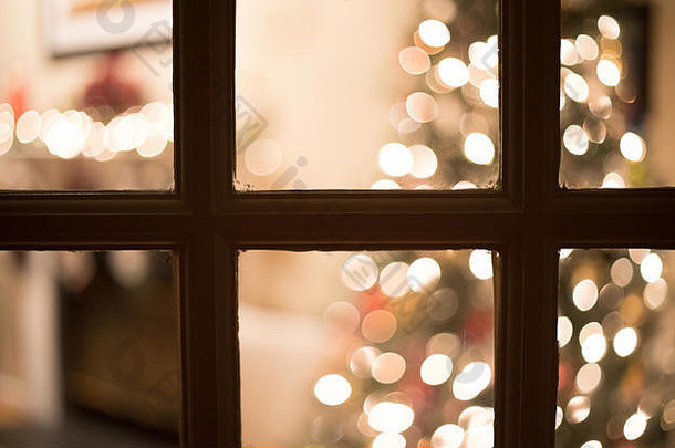 一张博克人的照片在晚上透过窗户窥视为圣诞节装饰的客厅。
