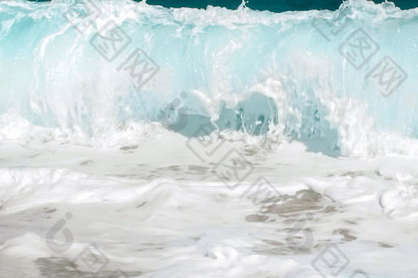 海浪在海岸上翻滚的特写图片。海潮席卷海岸