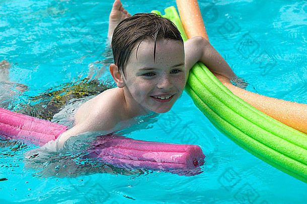 快乐的小男孩在室外游泳池学习游泳