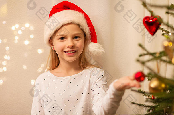 戴着圣诞帽装饰圣诞树的快乐女孩