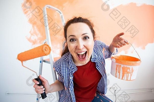在公寓里修理。有趣的女人用油漆粉刷墙壁。