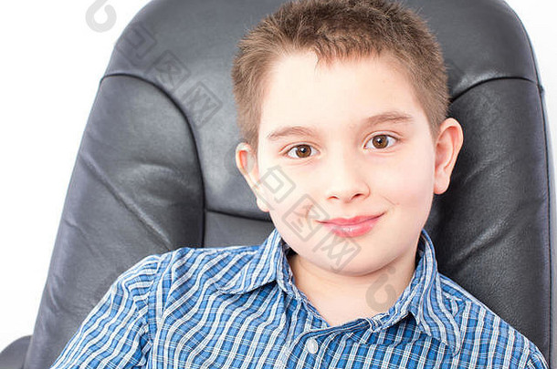 关闭微笑可爱的美国男孩坐着黑色的办公室椅子相机白色背景