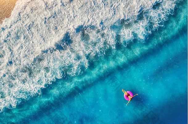 奥卢德尼兹透明海面上，一名女子在粉红色<strong>游泳</strong>圈上<strong>游泳</strong>的鸟瞰图。<strong>夏日</strong>的海景，女孩，海滩，美丽的海浪，蓝色的海水