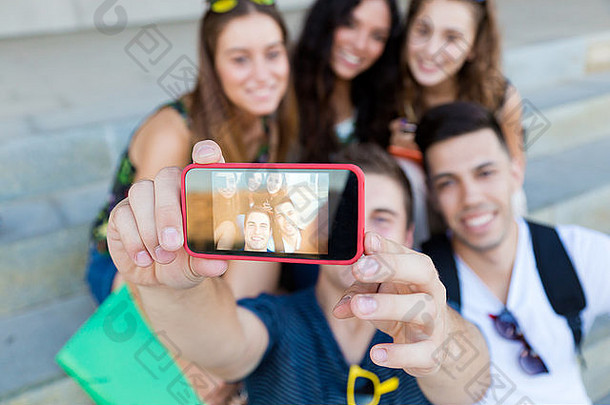 一群朋友在街上用智能手机拍照的户外肖像。