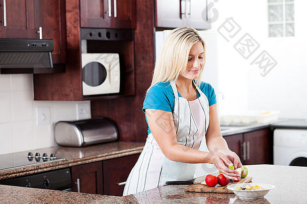 美丽的欧洲年轻女子在厨房做水果沙拉