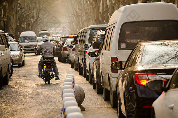 在中国西安的交通高峰时刻，汽车在塞车中耐心等待。摩托车移动<strong>自如</strong>。