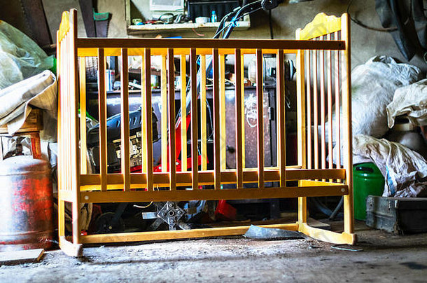 破旧的木制婴儿床、摇篮、凌乱的仓库里的婴儿床、车库。成长，人生历程理念
