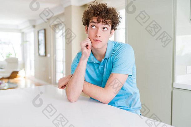 在家里穿着休闲蓝色t恤的年轻帅哥，双臂交叉，看起来很疲惫，对抑郁症感到厌倦。