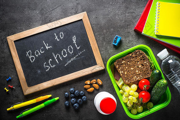 回到学校的概念。黑色背景的学校和办公室文具、背包和午餐盒。顶视图。