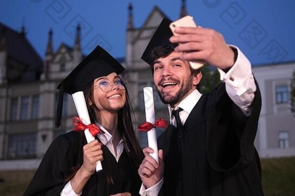 一对夫妇在向摄像机展示毕业证书时自拍。