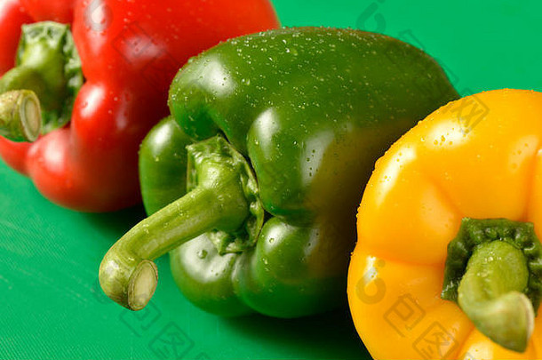 绿色砧板上的红色、绿色和黄色甜椒-符合食品卫生要求的正确颜色板