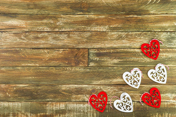 红色和白色的心形图案悬挂在棕色木质背景上。情人节的浪漫装饰。质朴、复古或复古风格