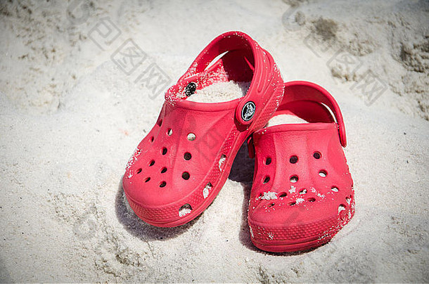 海滩上一双覆满沙子的鳄鱼鞋