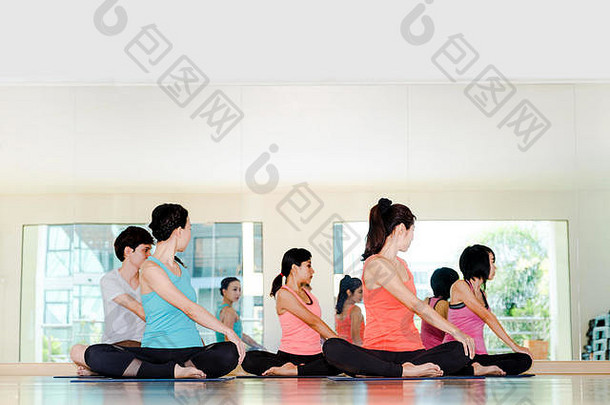 在工作室的瑜伽课上，一群人做着带着蛤蜊放松情绪的坐姿、冥想姿势、健康和健康的生活方式。