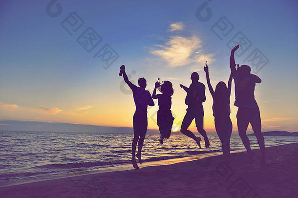 一群快乐的年轻人在美丽的夏日夕阳下在海滩上跳舞