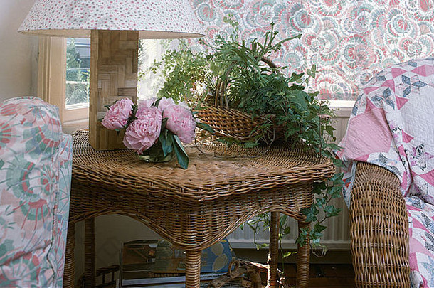 柳条桌上花瓶中的室内植物和粉色牡丹的特写镜头