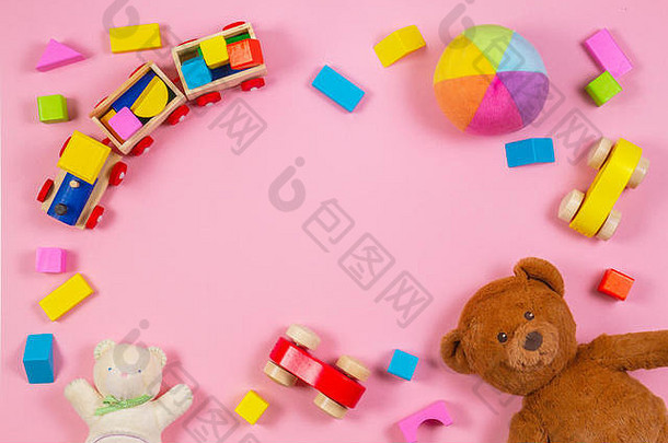 婴儿玩具框架，玩具熊，玩具车，木制火车，粉红色背景上的彩色砖块。俯视图