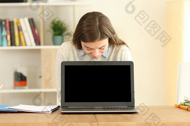 一名学生的前视图肖像，显示一个空白的笔记本电脑显示屏，并在家中观看