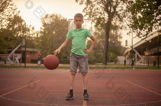 年男孩脸表达式运球球<strong>篮球</strong>法院在户外春天一天