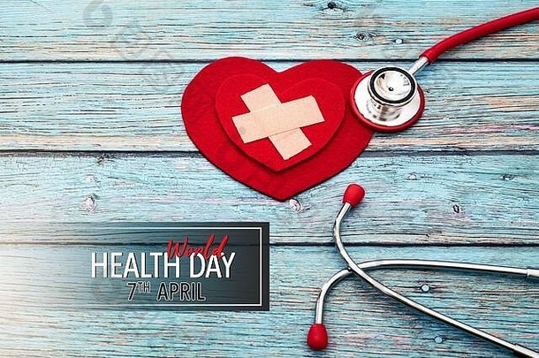 世界卫生日，医疗保健和医疗概念，蓝色木质背景上的红色听诊器和红色心脏