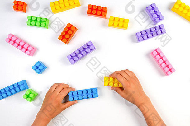 孩子们的手在白色背景上玩彩色塑料积木。