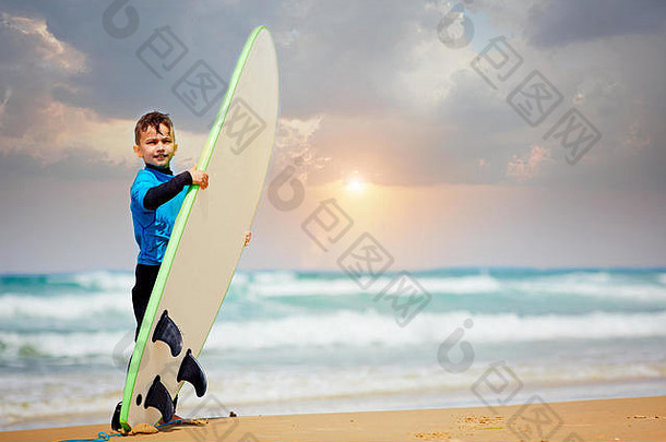 小男孩拿着冲浪板学习冲浪