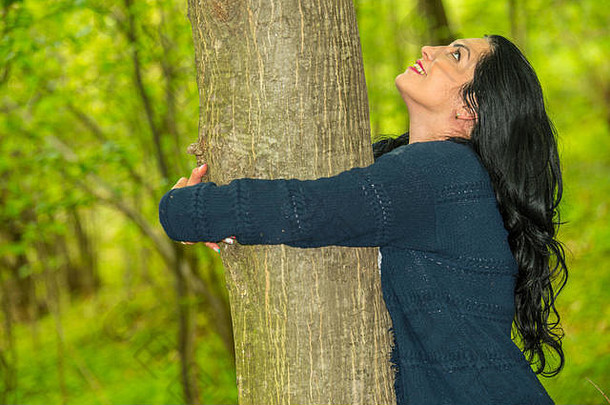 幸福的女人抱着一棵树向上看