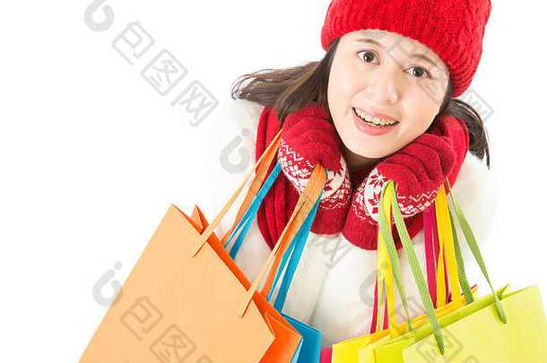 可爱的女人拿着五颜六色的购物袋。看摄像机的前视图。冬季圣诞促销概念。