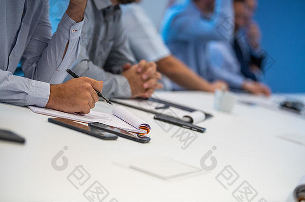 在工作会议上，一名男子手记笔记，在纸上写字
