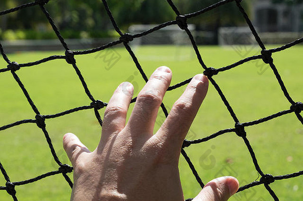 这名男子伸出手去触摸足球场的网格。