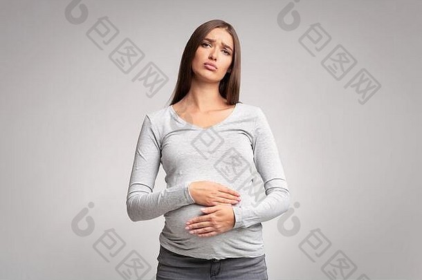 不开心怀孕了夫人触碰疼痛肚子站灰色的背景