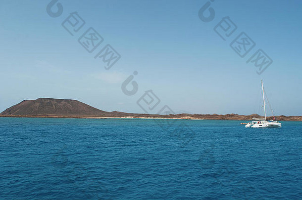 西班牙，大西洋，富尔特文图拉：一艘双体船，清澈的海水和洛沃斯小岛上火山口山的景色