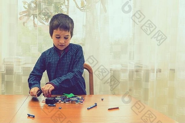那男孩在玩<strong>电动玩具</strong>。这孩子是由智力<strong>玩具</strong>玩的。一个穿蓝色衬衫的男孩精通电子技术。早期教育的概念