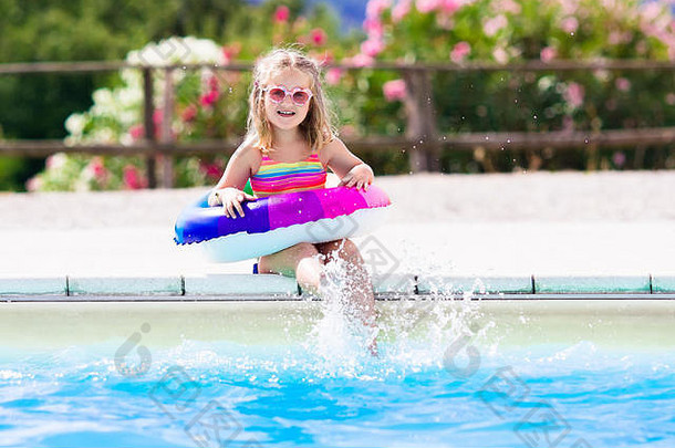 在炎热的<strong>夏日</strong>，快乐的小女孩在室外<strong>游泳</strong>池里玩着五颜六色的充气戒指。孩子们学习<strong>游泳</strong>。儿童水玩具。儿童解放军